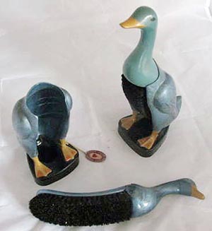 Two duck-shaped clothes brushes, one removed from its holder to show how they fit together.