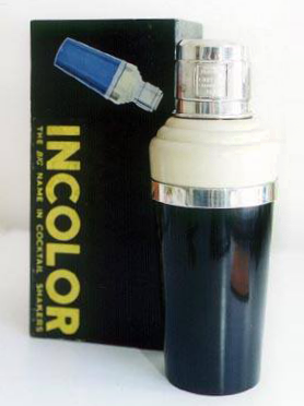 Cocktail shaker, lower part black, upper part white, with silver-coloured band around and silver cap, standing in front of its original box.